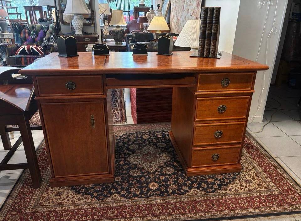Wooden desk with drawers on a patterned rug in a room setting